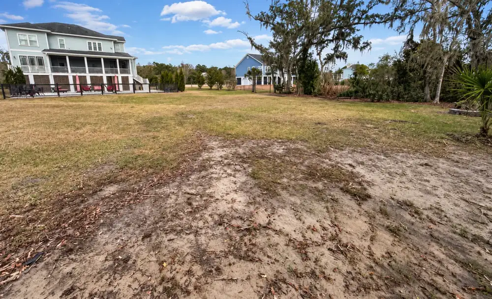 Back lot before: rutted sand and patchy grass behind a Lowcountry house