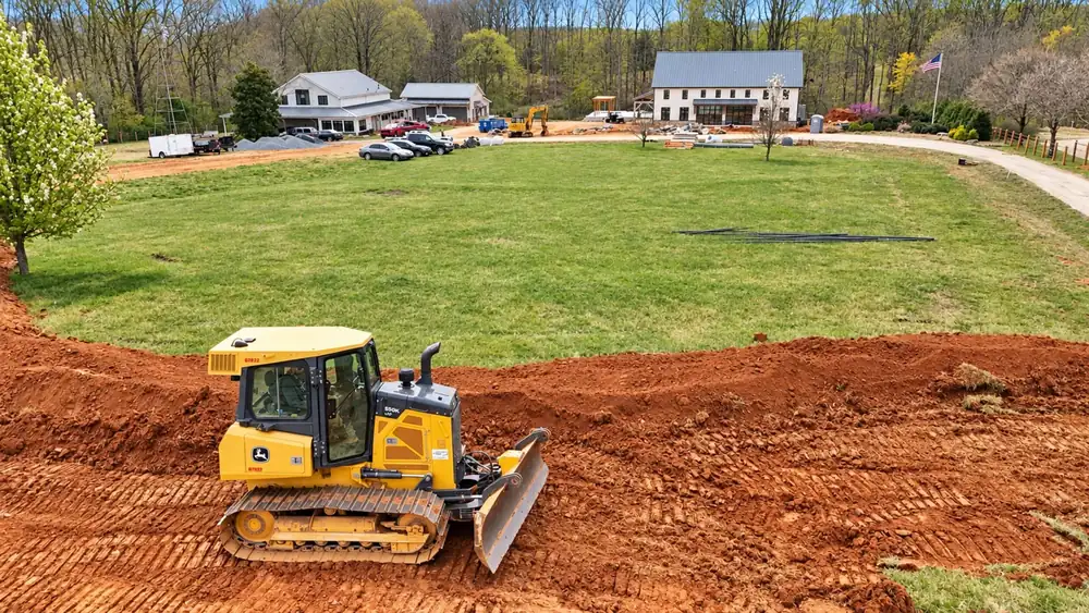Yellow dozer finishing the grade along a lawn edge